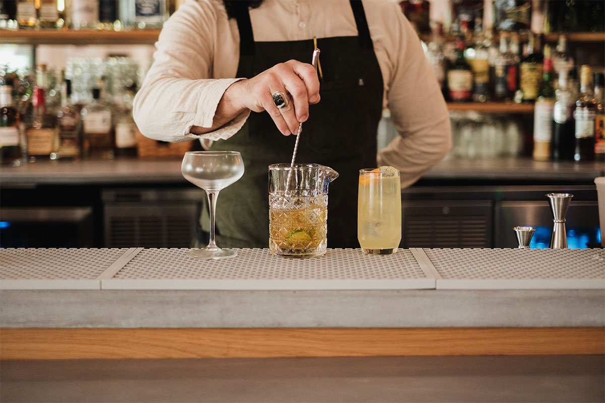 bartender preparando cocteles en bar estilizado moderno