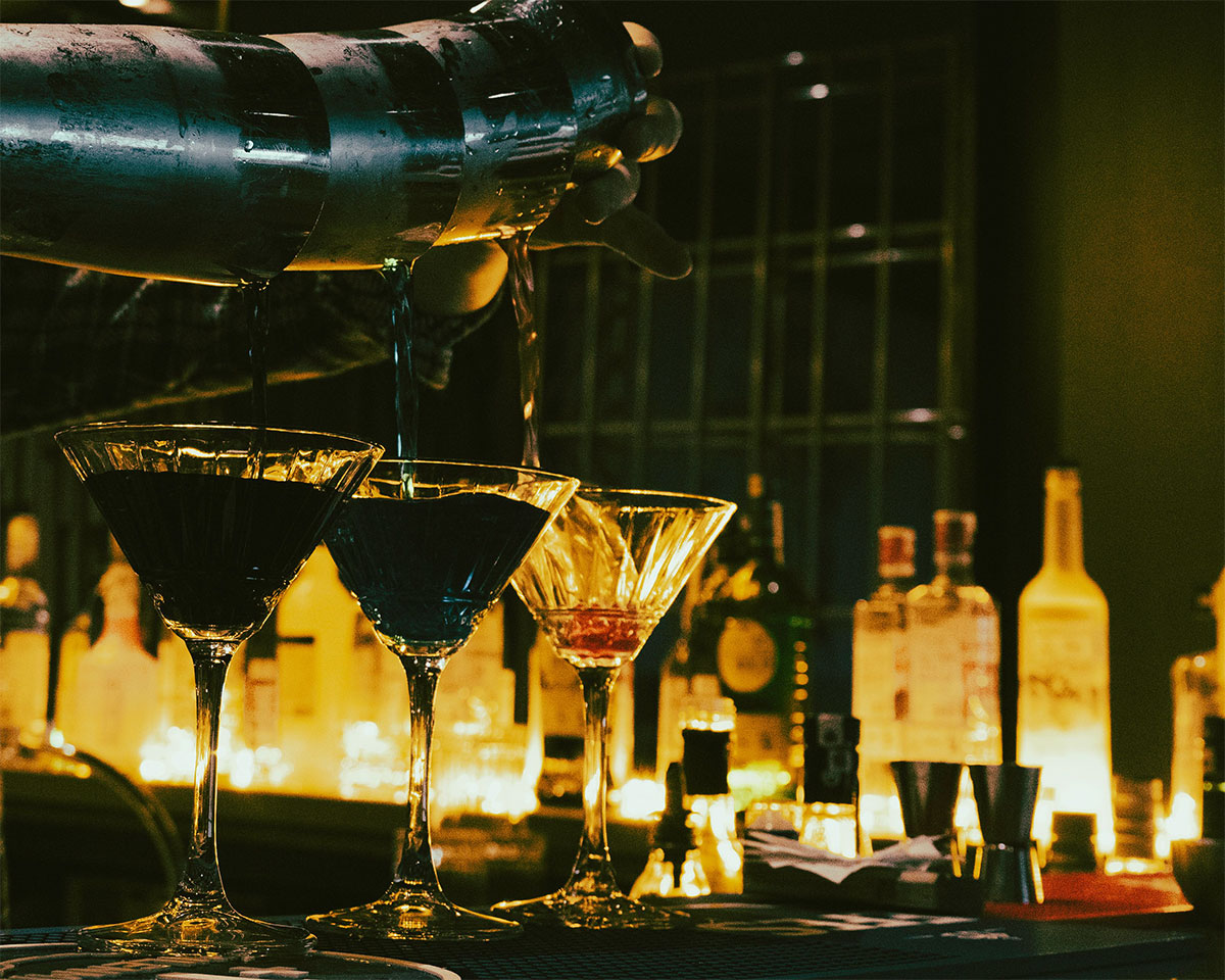 cocteles sobre barra iluminación tenue bar elegante coctelería de autor